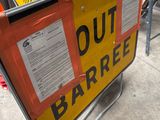 yellow and black out barricade sign sitting on the side of a road