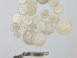 un bracelet en argent et quelques pièces de monnaie posés sur une surface blanche