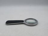 a magnifying glass with a black handle on a white surface