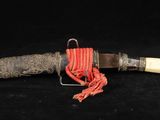 un vieux couteau avec un manche et une corde, sur fond noir