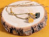a necklace with a coin and a chain on a piece of wood