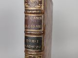 an old book sitting on top of a wooden table next to a white wall