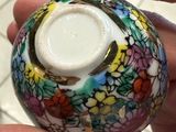 a person holding a colorful vase in their hand