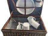 un panier de pique-nique en osier contenant des assiettes et des tasses