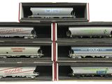 six model train cars are stacked up in a box on a white surface