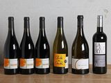 six bouteilles de vin sont alignées sur une table en bois