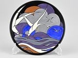 a picture of a decorative plate with seagulls flying over the water