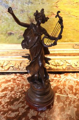 statue en bronze représentant une femme tenant une harpe posée sur une table en marbre