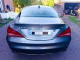 the back of a silver car parked in a driveway next to a house