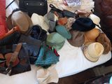 un lit sur lequel sont posés de nombreux chapeaux et sacs