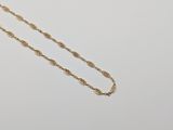 a gold chain necklace with a knot design on a white background