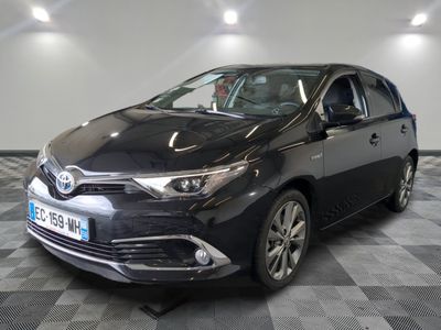 La Toyota Corollant est garée dans une grande pièce au sol carrelé en damier.