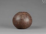 an old brown vase with designs on it on a gray surface