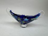 bol en verre bleu orné de fleurs et de feuilles, posé sur un fond blanc