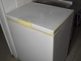 a small white refrigerator in a kitchen with a sink