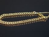 gros plan d'un bracelet en chaîne en or sur une surface noire