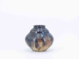 a blue and brown vase sitting on a white surface