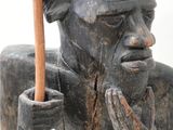 statue d'un homme tenant un bâton en bois et portant un chapeau