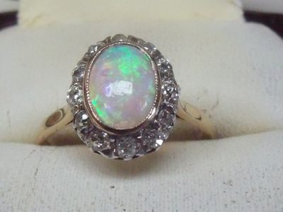an oplite and diamond ring on display in a ring holder