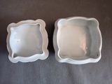 two white dishes sitting on a table next to each other