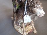 a figurine of a man riding a goat holding a cup