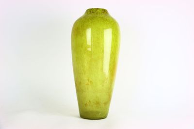 un vase vert posé sur une surface blanche