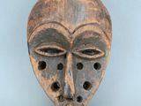 une image représentant un masque en bois percé de trous au niveau du visage