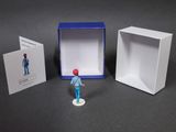 a small figurine of a man standing in front of a box