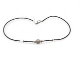 un bracelet en cordon noir orné d'une perle et muni d'un fermoir en argent
