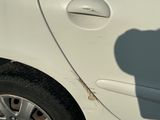 a small white car parked in a parking lot with a shadow of a person on the side of the car