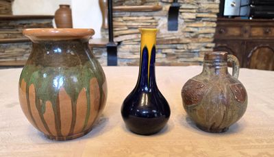 three vases sitting on a table with a stone wall in the background