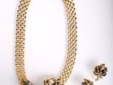 une photo d'un ensemble composé d'un collier et de boucles d'oreilles sur fond blanc