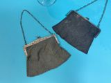two small purses are sitting on a blue surface next to a glass of wine