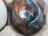 a white egg and a blue and red vase in a box
