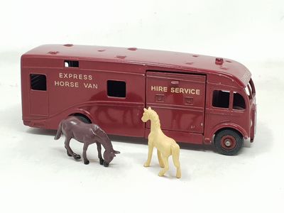 deux chevaux miniatures placés à côté d'un bus rouge