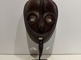 an image of a wooden mask on a stand on a white surface