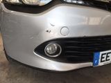 the front end of a silver car with a number plate on it