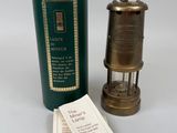 une lampe à huile ancienne en laiton, avec un étui vert et une étiquette