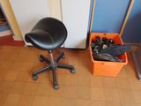 un tabouret noir posé à côté d'un bac à chaussures orange