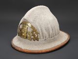 beige wool hat with brass buckle on top of a wooden base