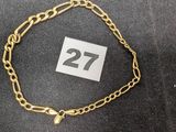 un gros plan d'un bracelet à chaîne en or sur lequel figure le chiffre 27