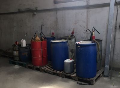 trois fûts bleus posés sur une palette dans un garage