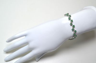 bracelet orné de pierres vertes sur la main d'un mannequin blanc
