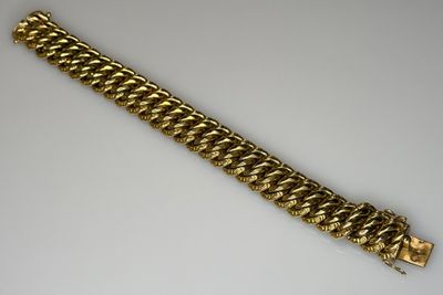 a close up of a gold chain bracelet on a white surface