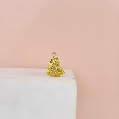 un pendentif en forme d'ourson doré posé sur un bloc de marbre blanc