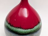 a red vase with a green stripe on it