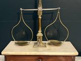an antique brass scale with two glass vases on top of it