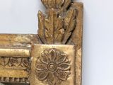 a mirror that has a gold frame with a flower on it