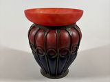 a red bowl sitting on top of a black vase
