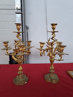 une paire de chandeliers anciens en laiton posés sur une nappe rouge